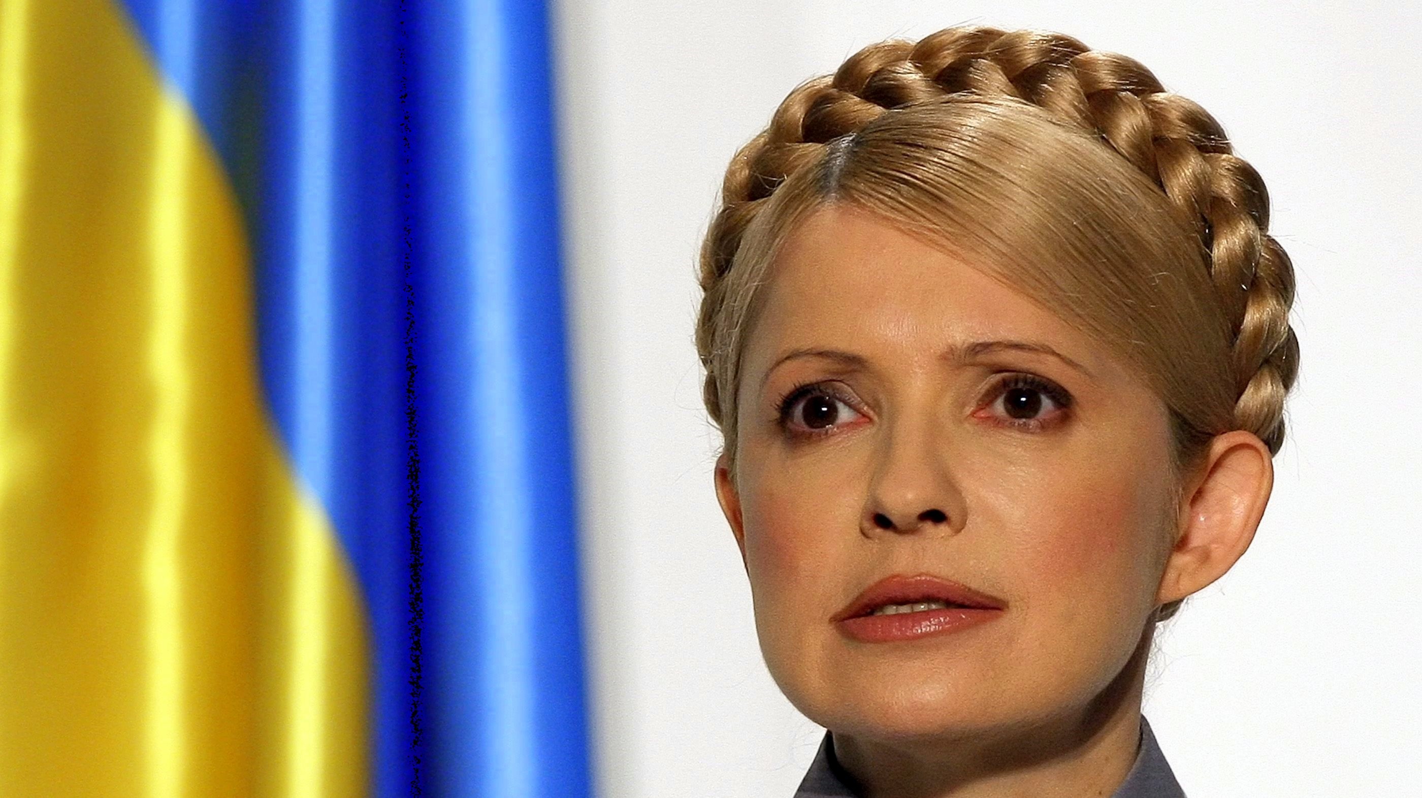 Julija Tymošenková_detail tváre_vlajka_ukrajinská za ňou
